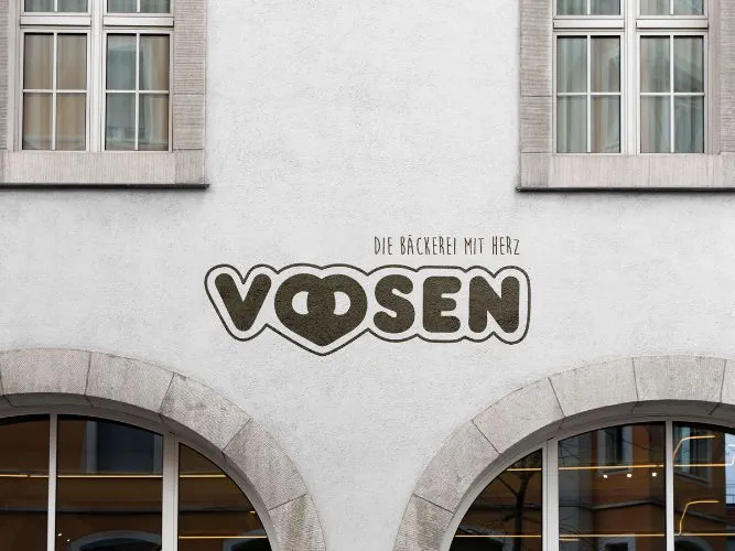 Außenansicht einer Filiale der Bäckerei Voosen mit aufgemalten Logo auf der Hauswand
